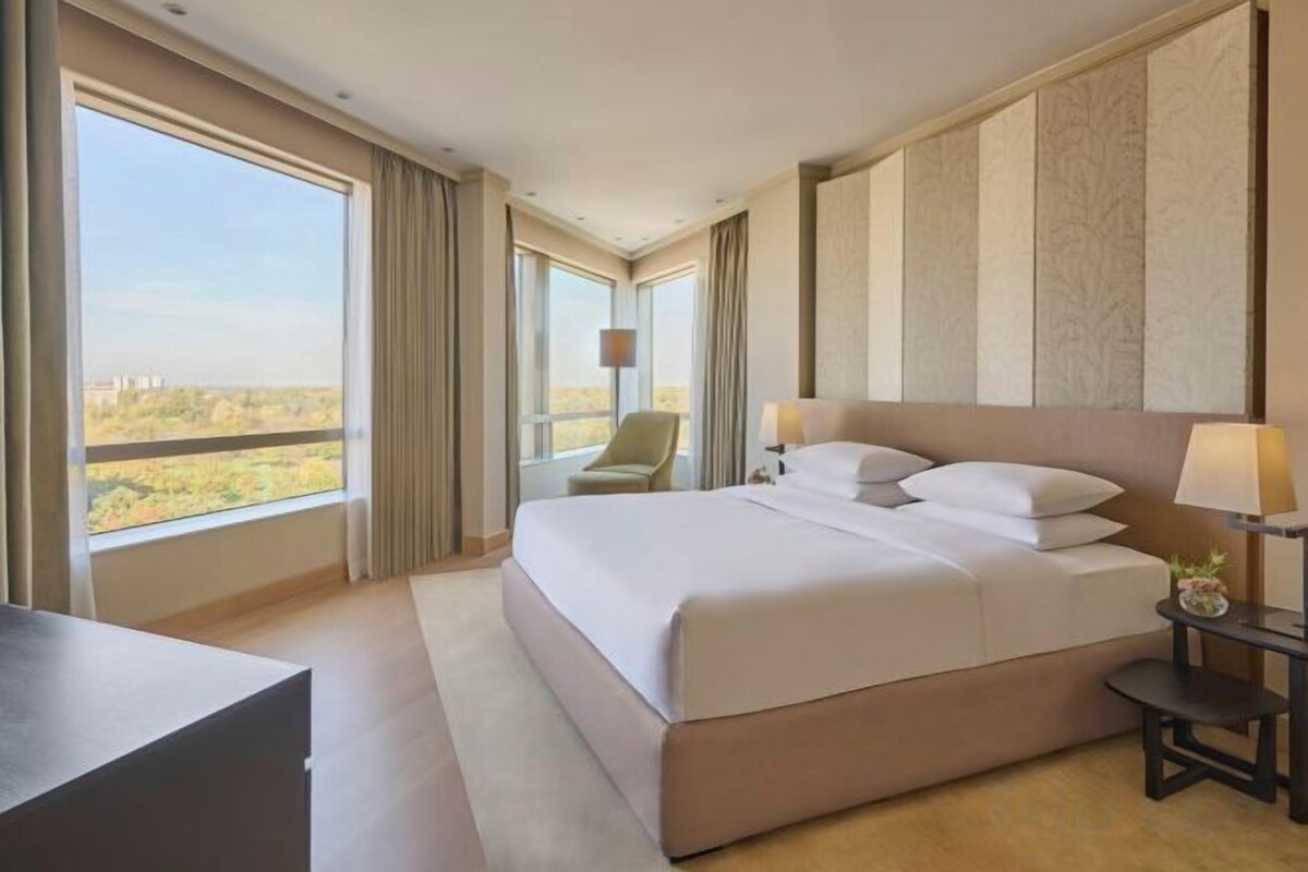 A hotel room with a large bed, a desk, and a chair.