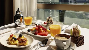 A breakfast table with various food items, a coffee cup, and a view of a cityscape through a window. - Hyatt Regency Belgrade (Belgrade)