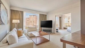 A modern hotel room with a sofa, coffee table, TV, and a view of a high-rise building. - Hyatt Regency Belgrade (Belgrade)