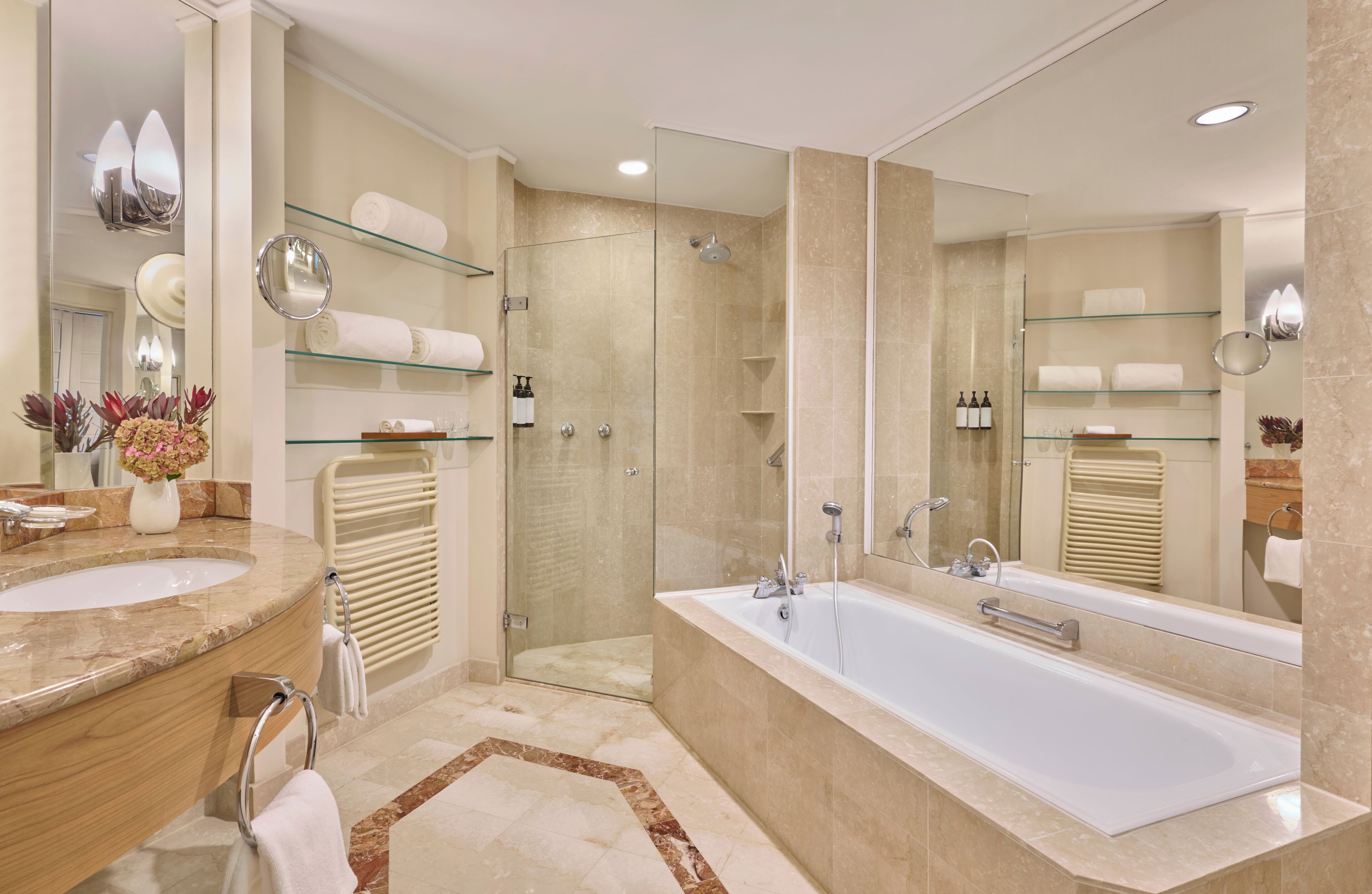 Un baño moderno con una bañera grande, ducha con cerramiento de vidrio y tocador con encimera de mármol.