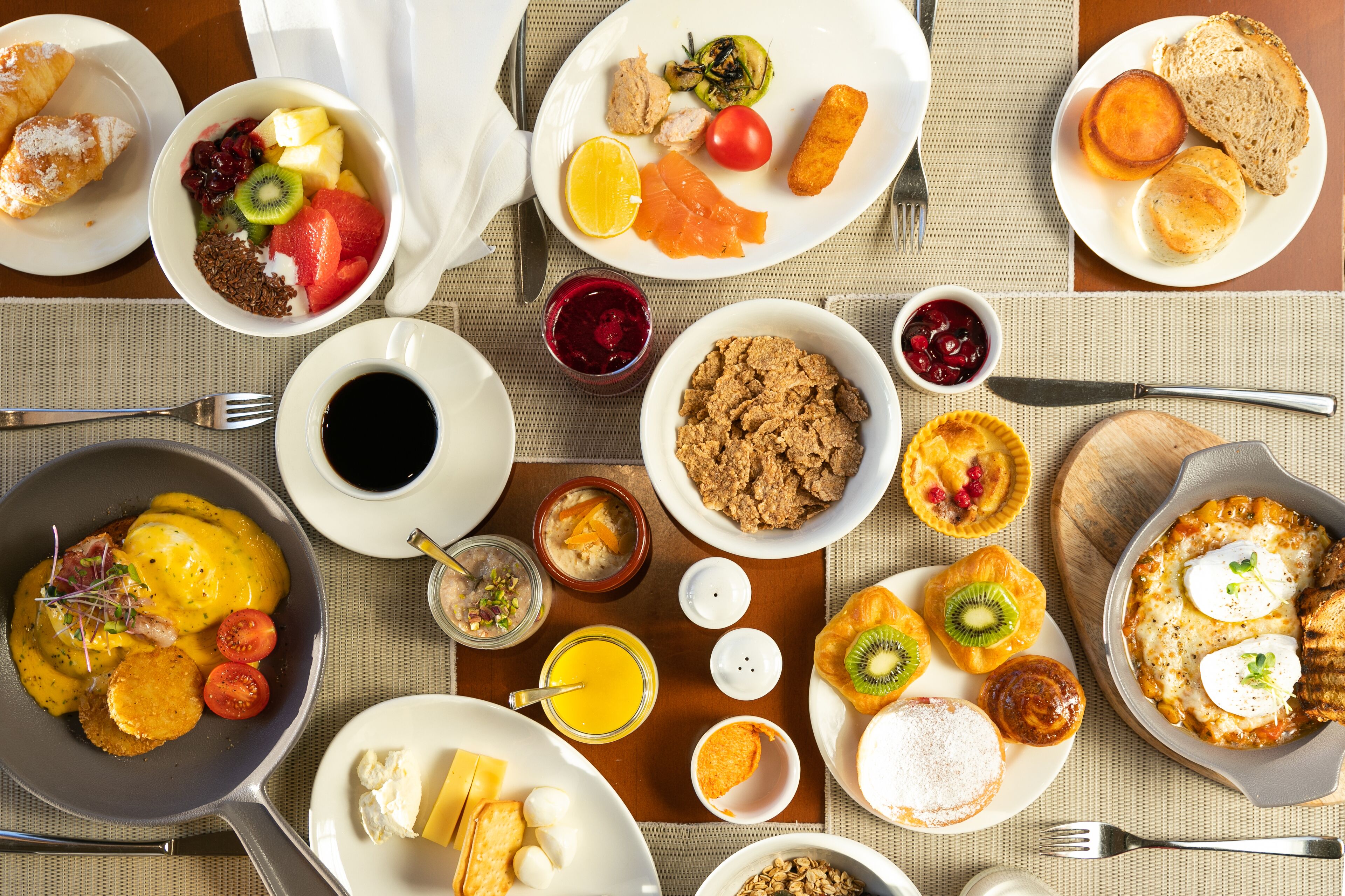 Un ricco buffet della colazione con diversi piatti, tra cui frutta, dolci e bevande.