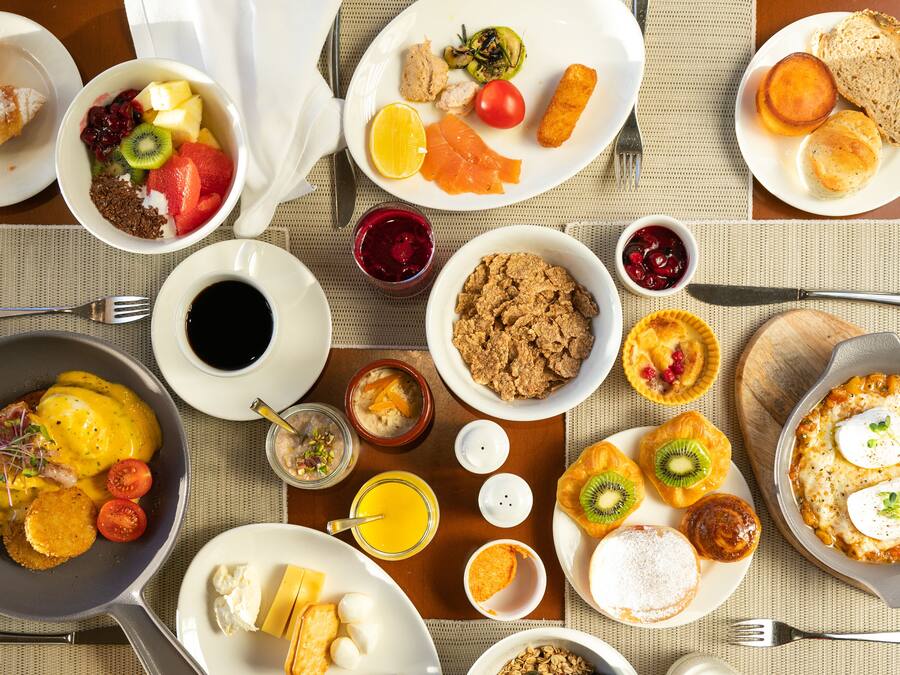 Un ricco buffet della colazione con diversi piatti, tra cui frutta, dolci e bevande.