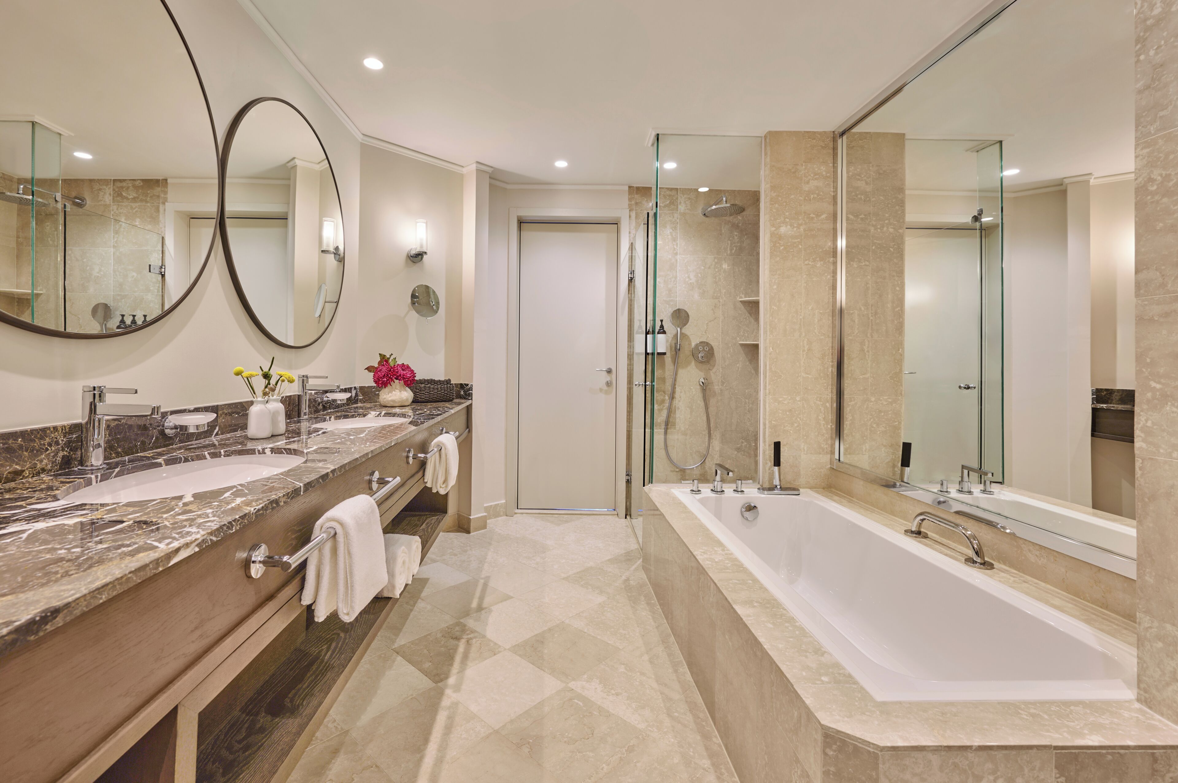 Ein modernes Badezimmer mit einer großen Badewanne, zwei Waschbecken und einer Duschkabine.