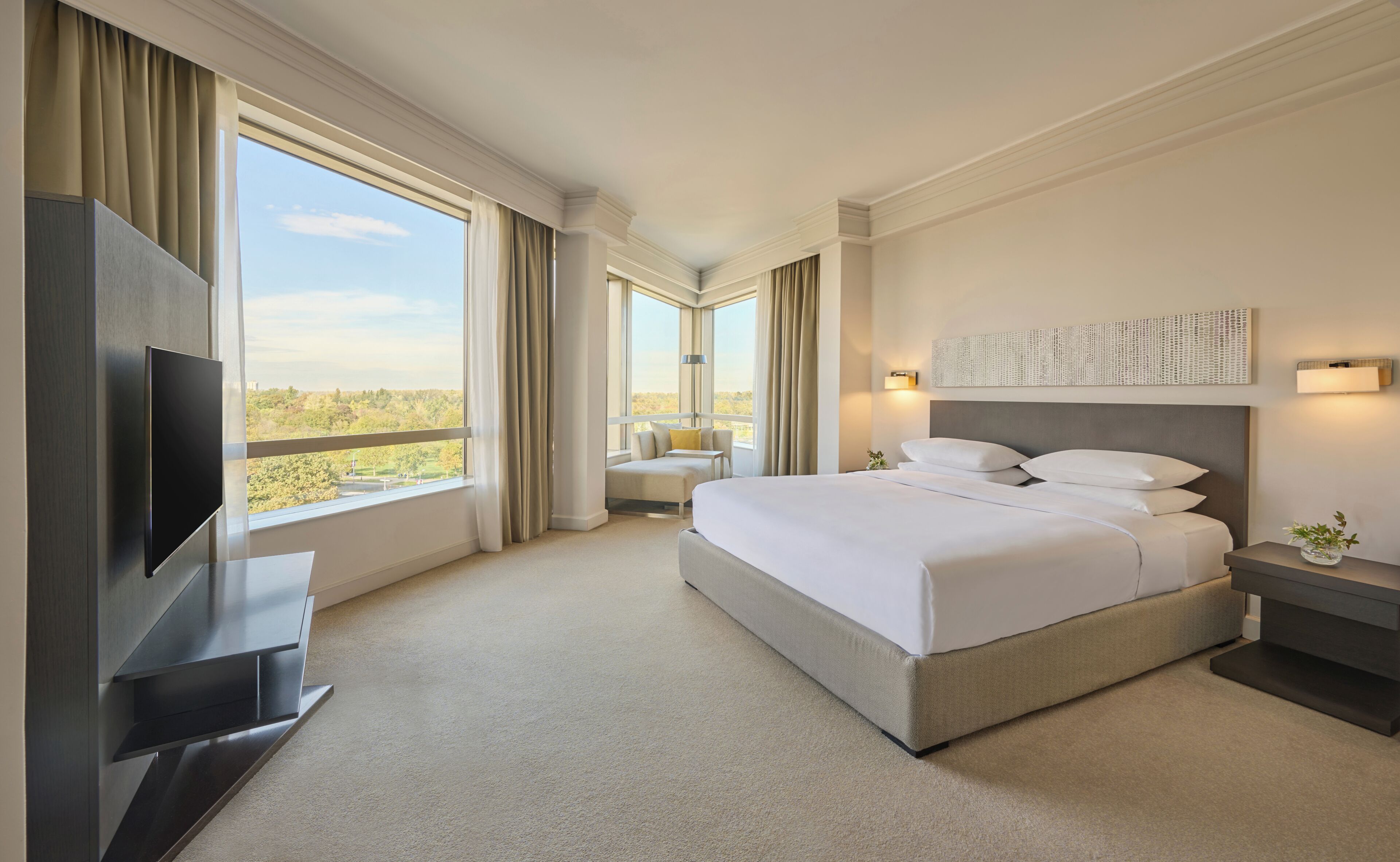 Habitación de hotel con una cama grande, televisión, escritorio y vistas al exterior.