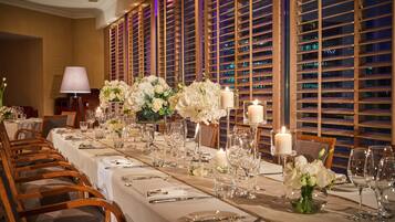 A long dining table set with white tablecloths, candles, and floral centerpieces.