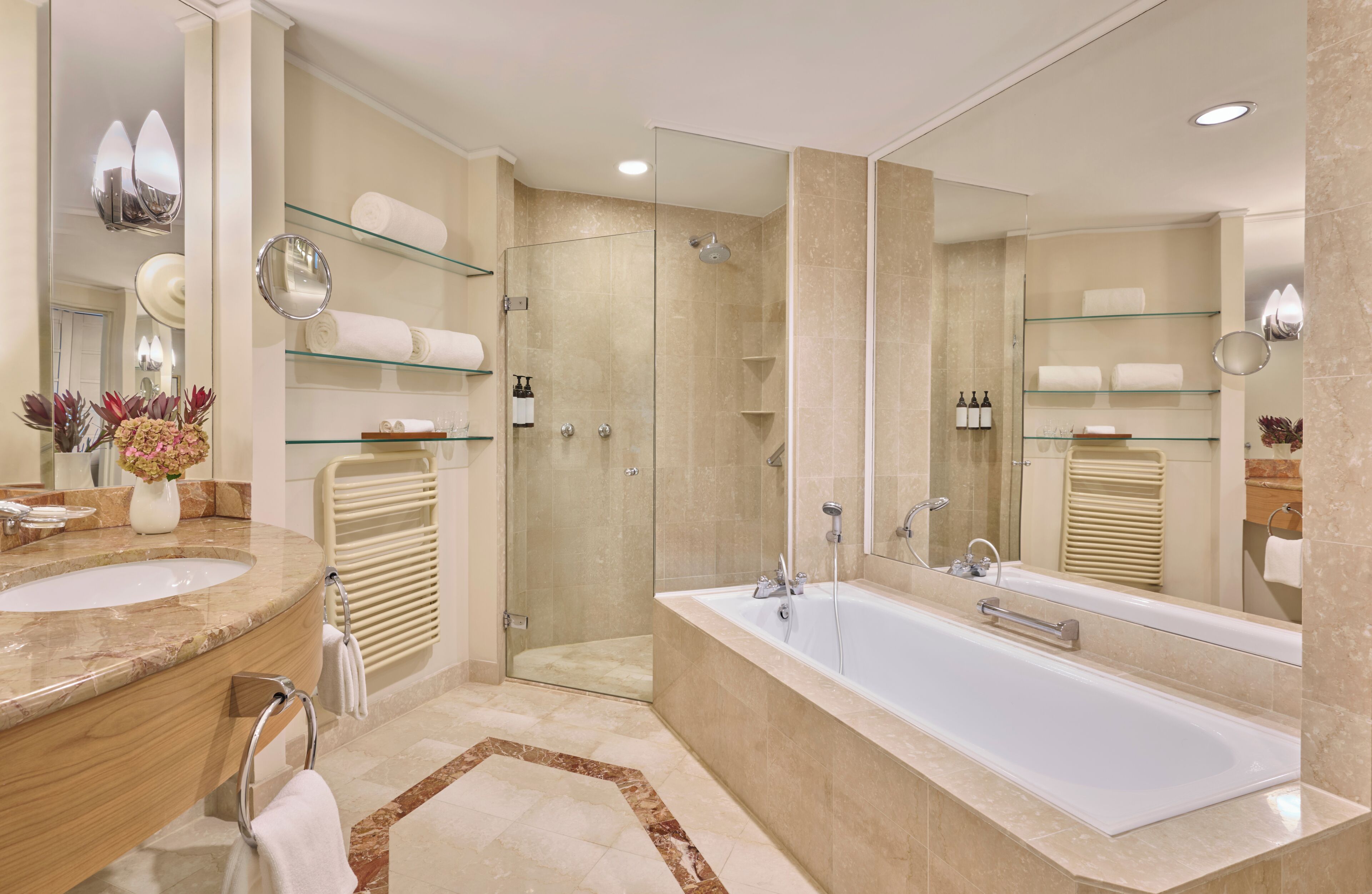 Une salle de bain moderne dotée d’une grande baignoire, de deux vasques, d’une douche à parois de verre et d’un meuble-lavabo avec un miroir.