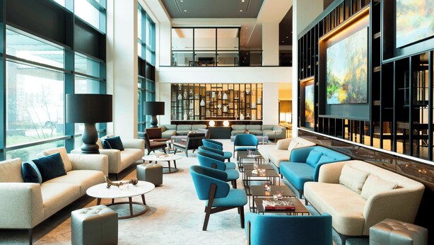 A spacious lobby with multiple seating areas, including sofas and armchairs, arranged around a central coffee table. - The Hague Marriott Hotel (The Hague)