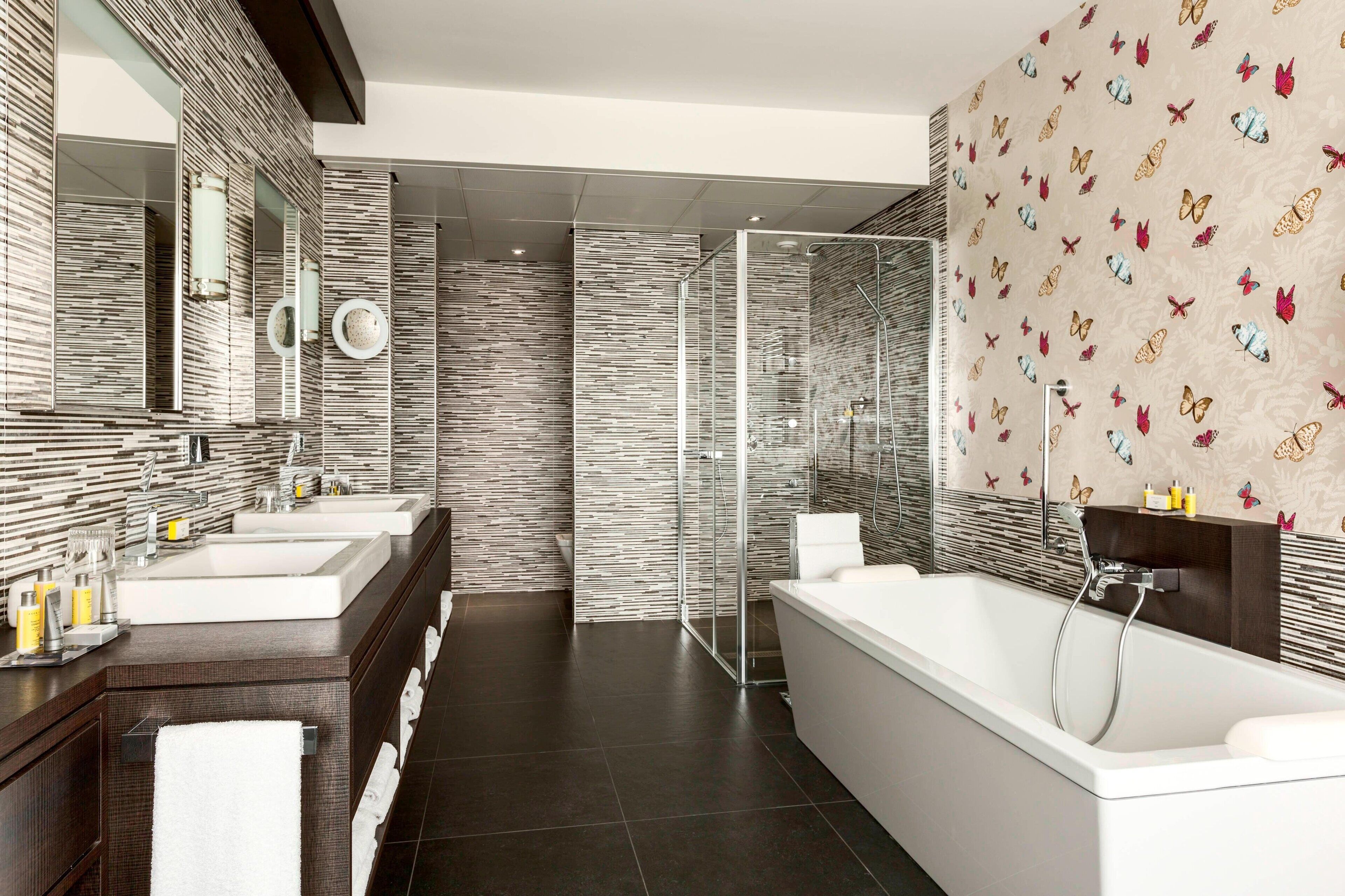 A modern bathroom with two sinks, a large bathtub, and a glass shower enclosure.
