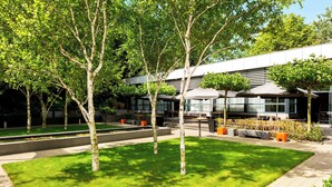 A courtyard with trees, outdoor seating, and a modern building with large windows. - The Hague Marriott Hotel (The Hague)