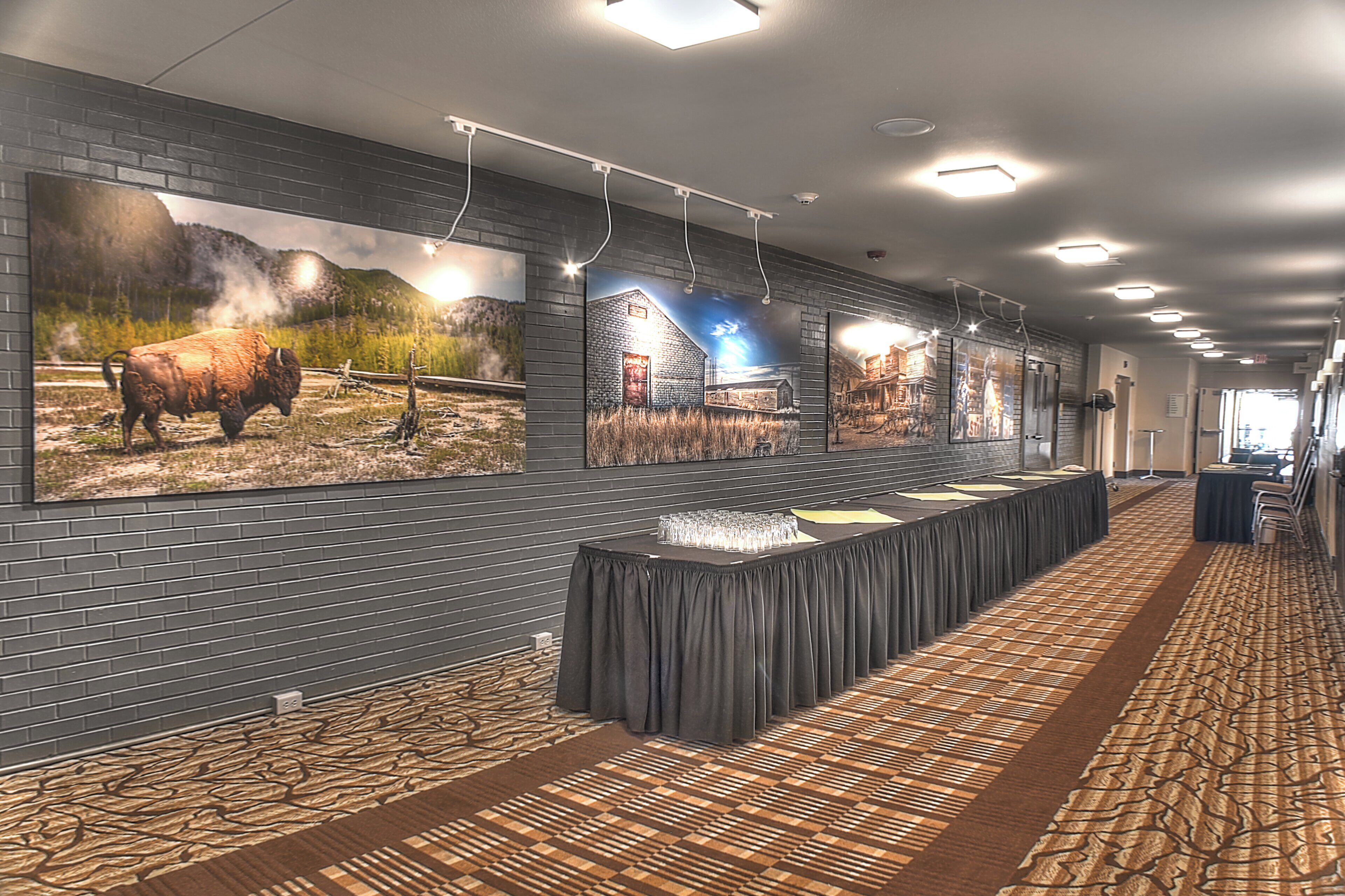 A long reception area with a reception desk, a patterned carpet, and a wall with large landscape paintings.