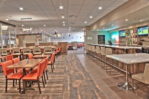 A spacious restaurant with multiple dining areas, a bar, and sports screens.