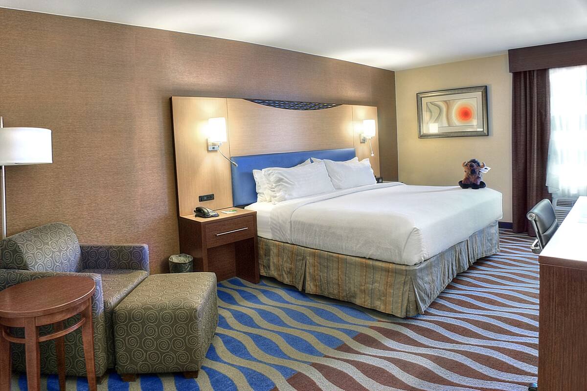 Een hotelkamer met een groot bed, een bureau, een stoel, een kleine tafel en een bank.