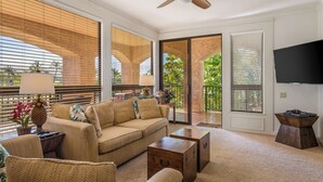 A spacious living room with a sofa, coffee table, and a flat-screen TV. - Shores at Waikoloa (Waikoloa)
