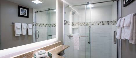 A modern bathroom with a glass-enclosed shower, a granite countertop sink, and a large mirror.