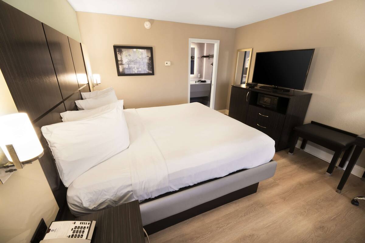 A hotel room with a large bed, a TV, a desk, and a wardrobe.