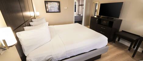 A hotel room with a large bed, a TV, a desk, and a wardrobe.