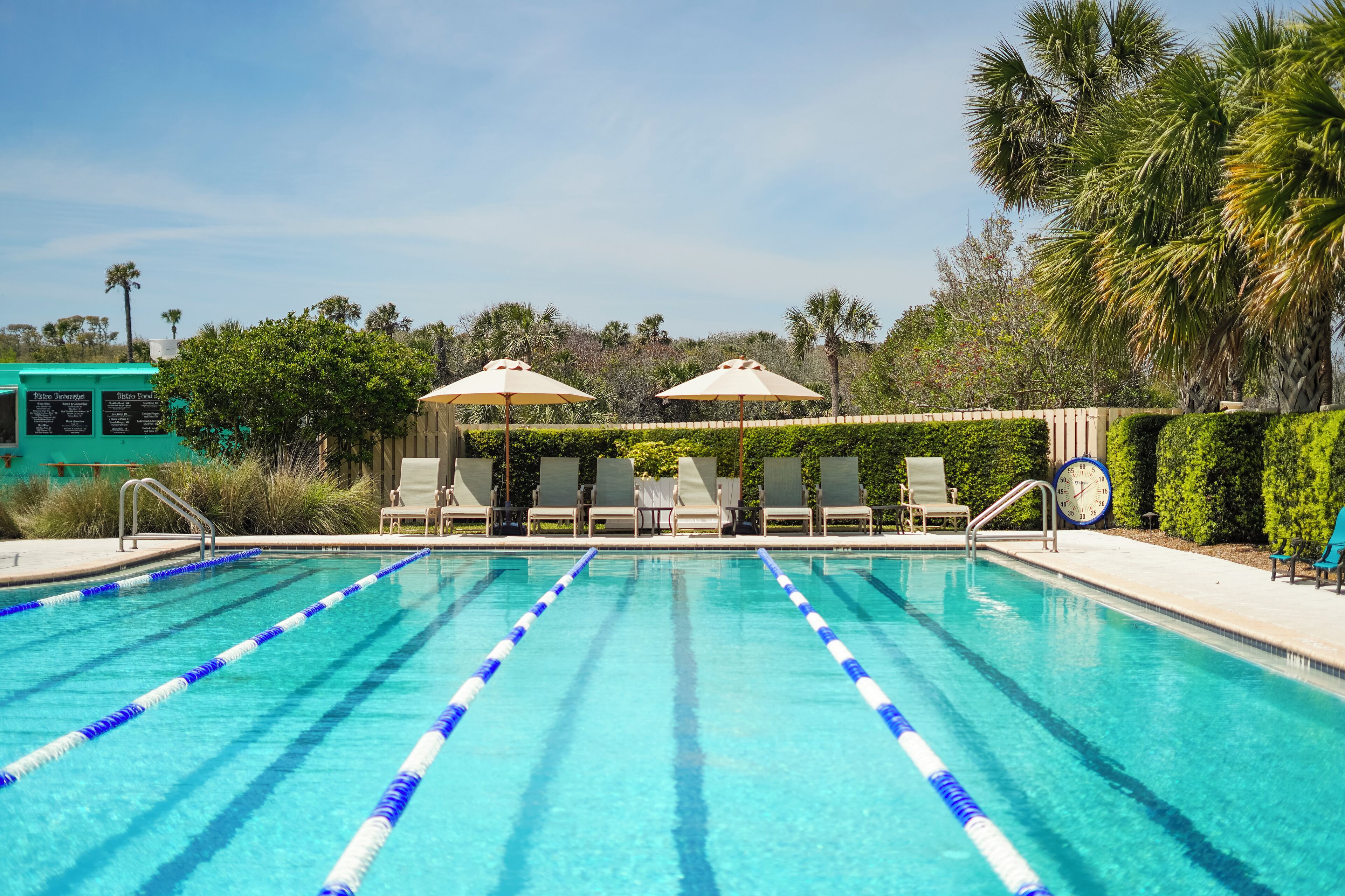 A swimming pool with lane dividers, lounge chairs, and umbrellas.