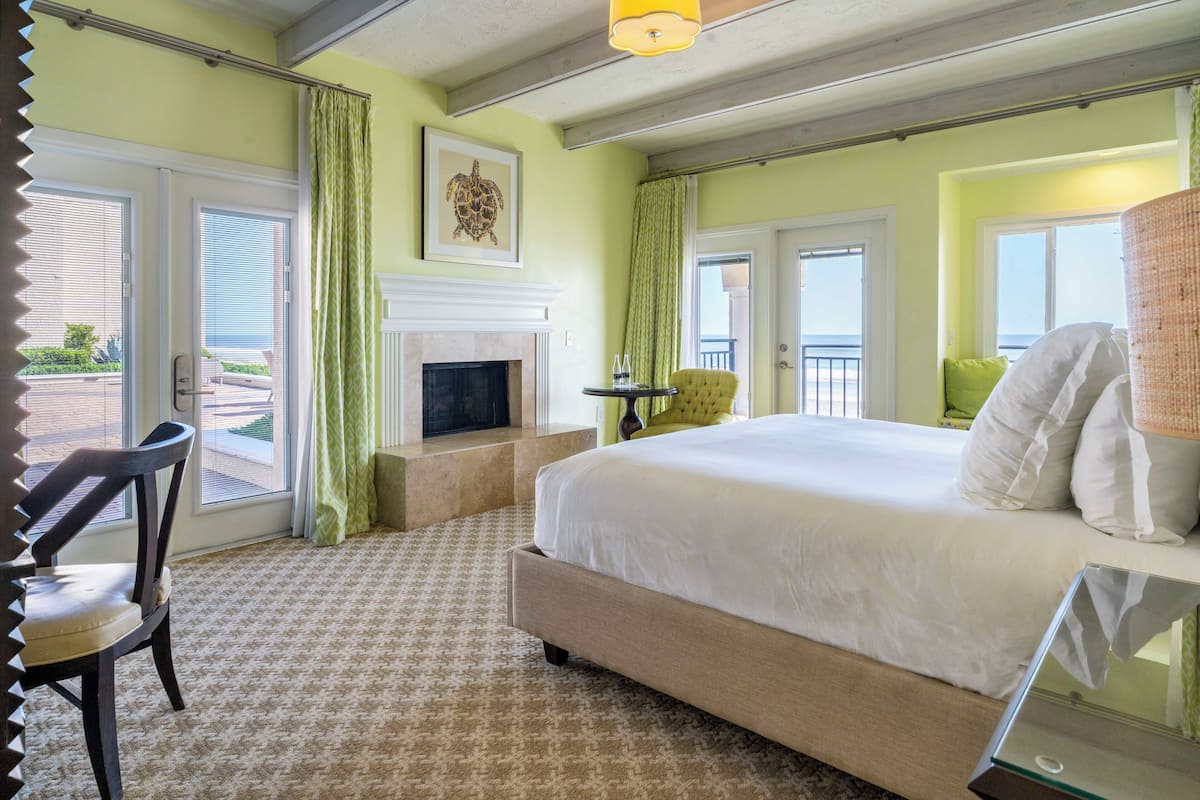 Une chambre d’hôtel avec un lit, une chaise, une cheminée, un balcon et une vue sur l’extérieur.