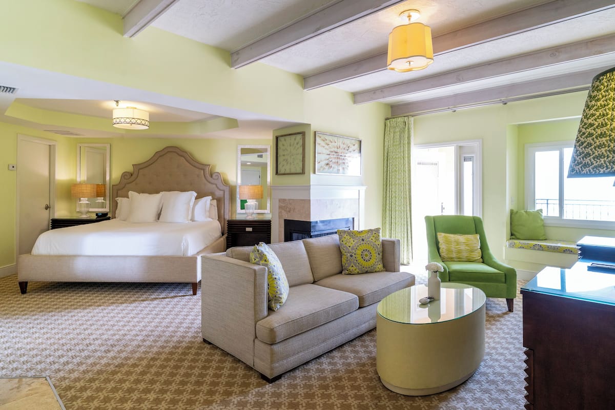 Une chambre d’hôtel comprenant un lit, un canapé, un fauteuil et une table basse ronde.