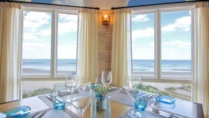 A dining table set for two with a view of the ocean through large windows. - The Lodge and Club at Ponte Vedra Beach (Ponte Vedra Beach)