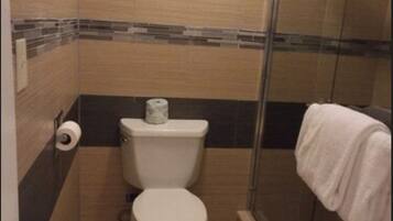 A small, modern bathroom with a toilet, a shower, and a towel rack.