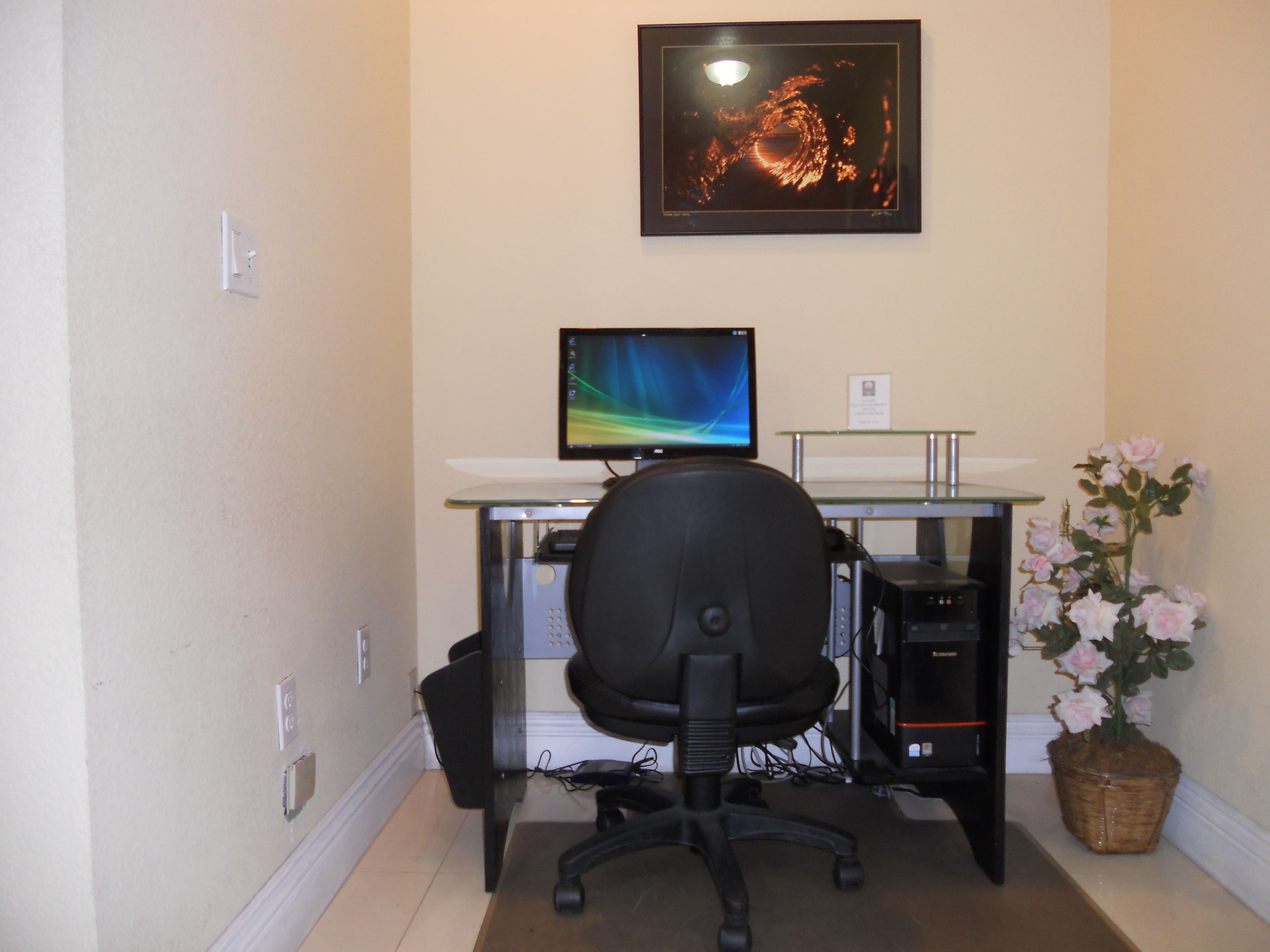 Una oficina en casa con escritorio, computadora, silla y un cuadro en la pared.