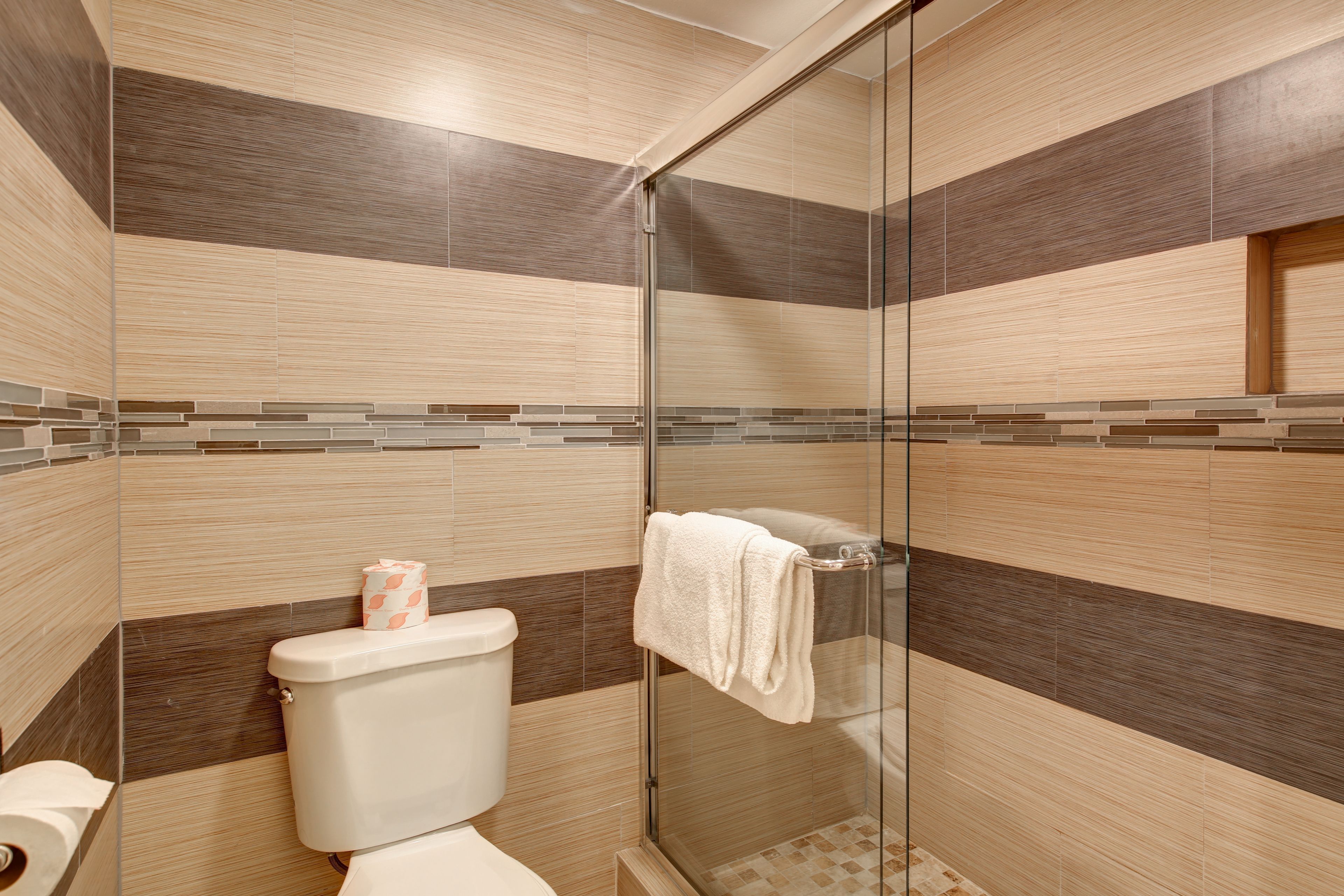 A modern bathroom with a glass shower enclosure, a toilet, and a towel rack.