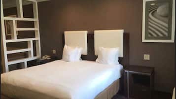 Habitación de hotel con una cama grande, dos mesitas de noche y una unidad de almacenamiento empotrada.