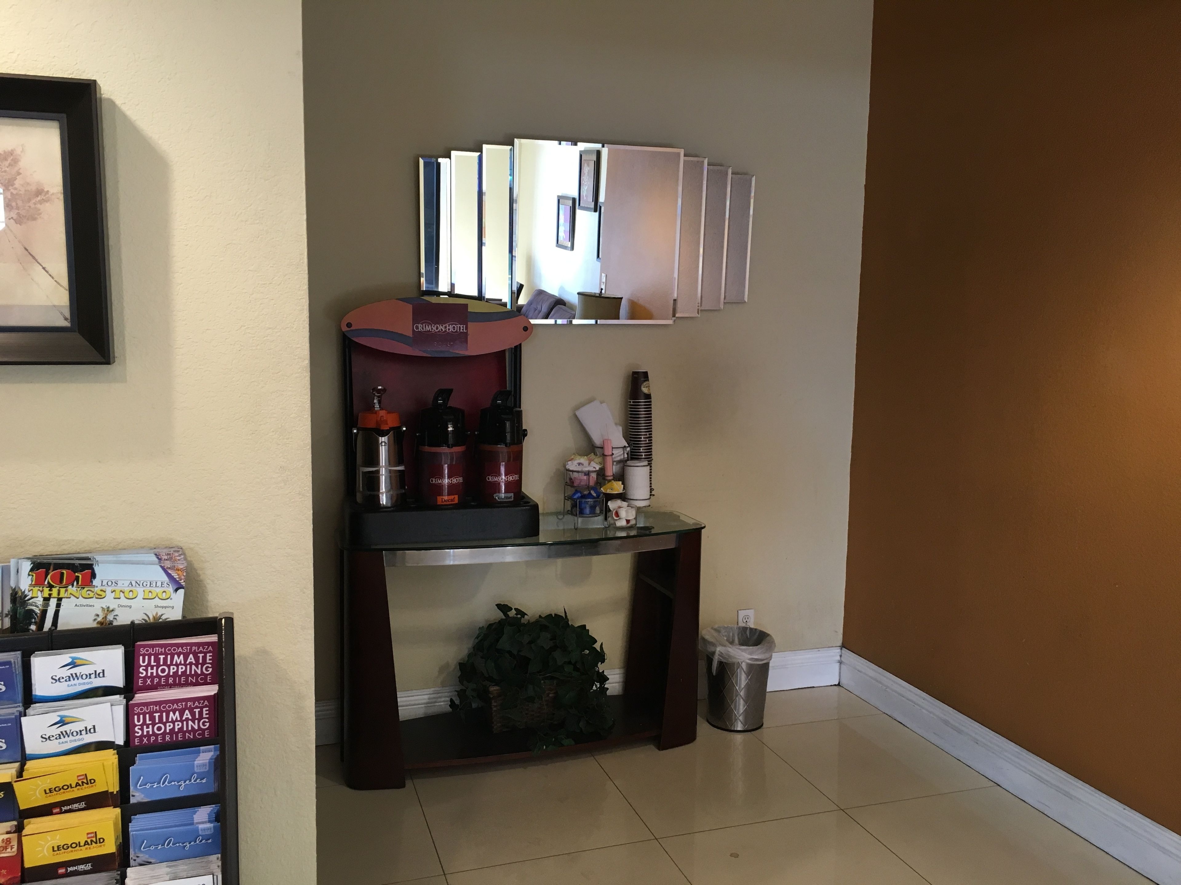 A hotel reception area with a coffee machine, a trash can, and a display of local attractions.