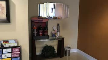 Ein Hotel-Empfangsbereich mit Kaffeeautomaten, Mülleimer und einer Präsentation lokaler Sehenswürdigkeiten.