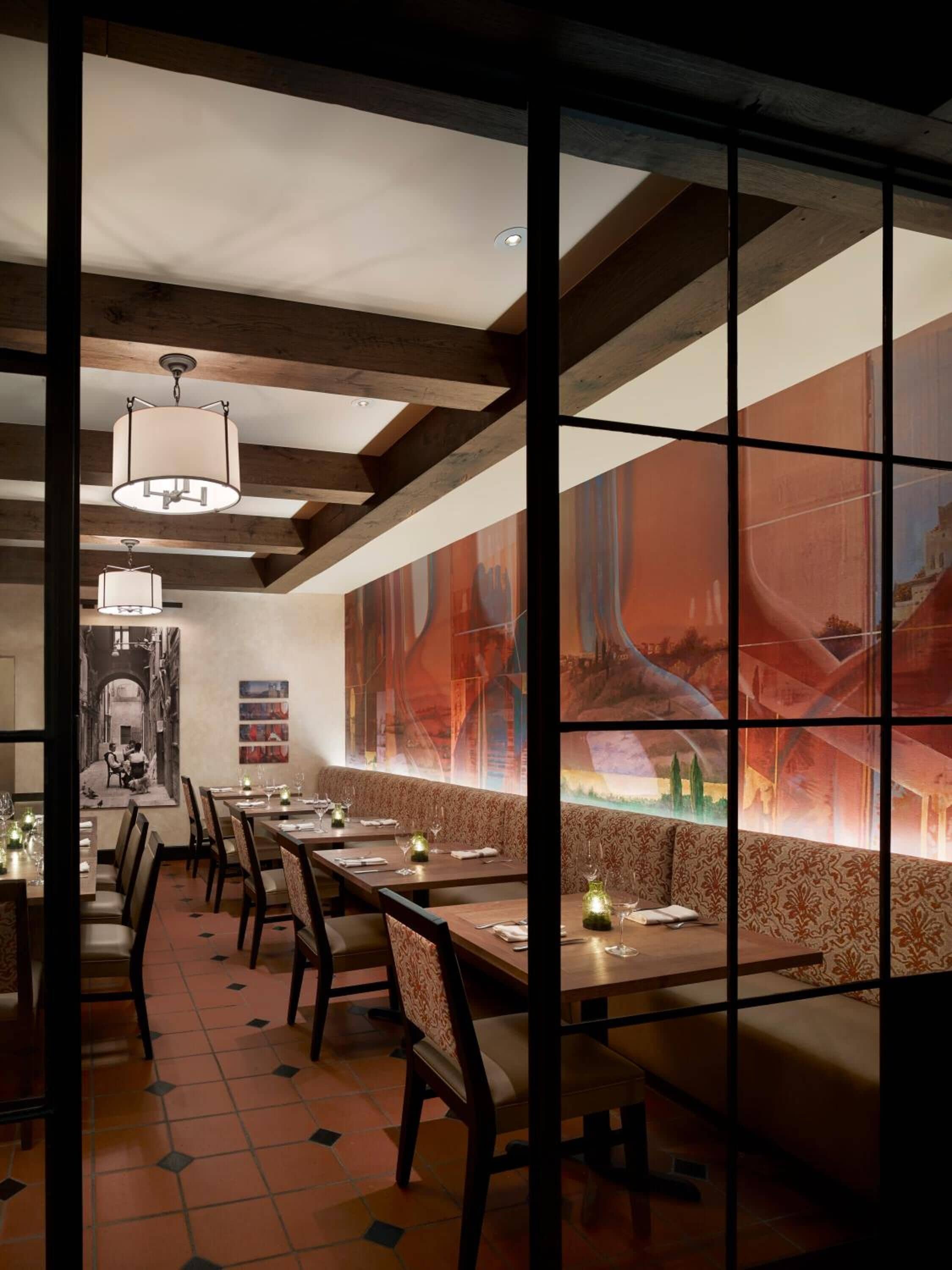 Un restaurant doté de longues tables communes, de poutres en bois et d’une grande fresque murale au fond de la salle.