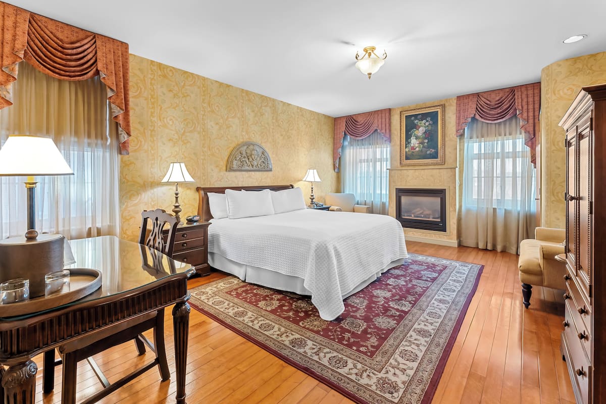 A spacious bedroom with a large bed, a dining table, and a fireplace.