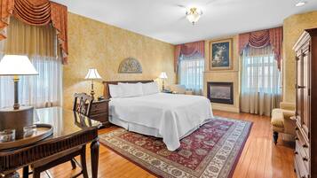 A spacious bedroom with a large bed, a dining table, and a fireplace.