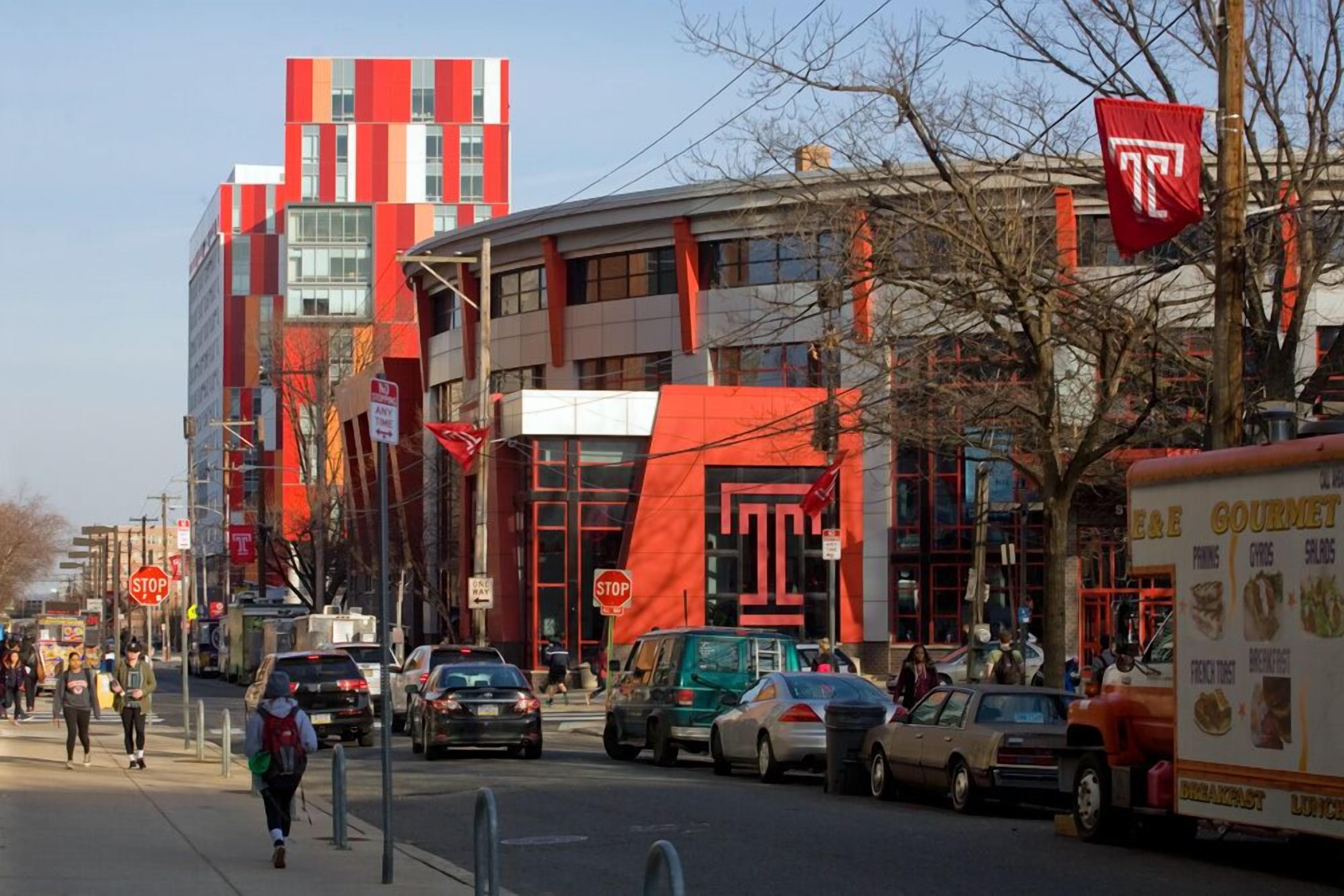 A busy urban street with modern buildings, a food truck, and pedestrians.