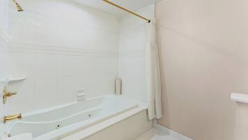 Un baño moderno con una bañera grande, un cabezal de ducha y un inodoro.