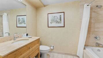 A modern bathroom with a sink, toilet, and bathtub. There are framed pictures on the wall and a shower curtain.