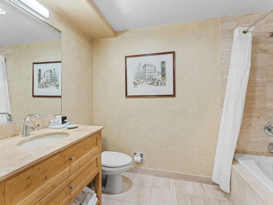 A modern bathroom with a sink, toilet, and bathtub. There are framed pictures on the wall and a shower curtain.