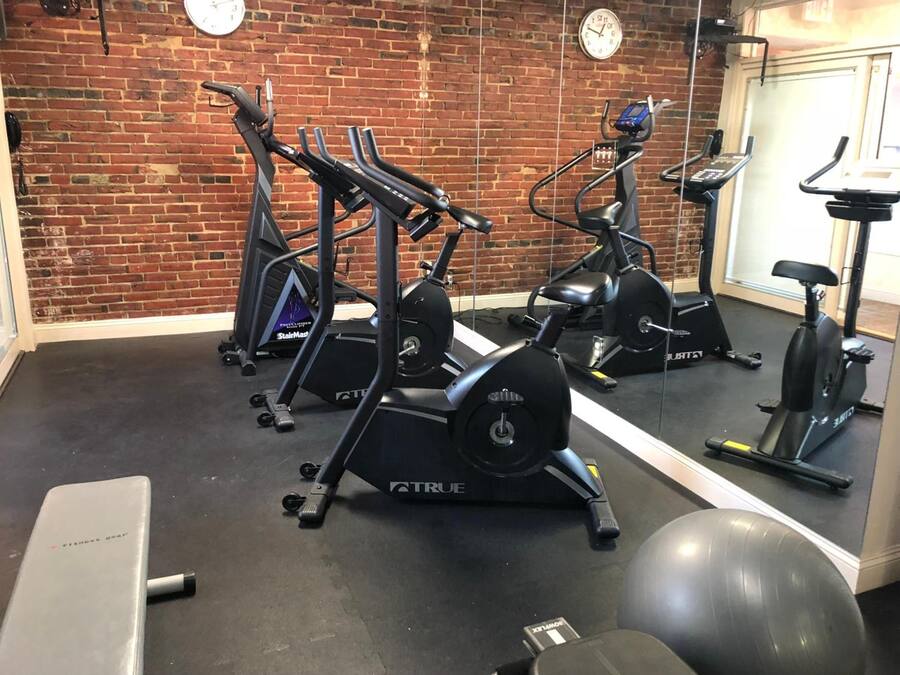 Uma academia com várias bicicletas de exercício e um espelho grande na parede.