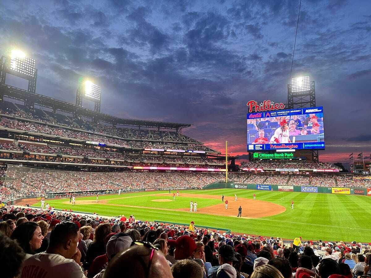 Un estadio de béisbol con varios niveles de asientos, un marcador digital grande y una multitud de espectadores.