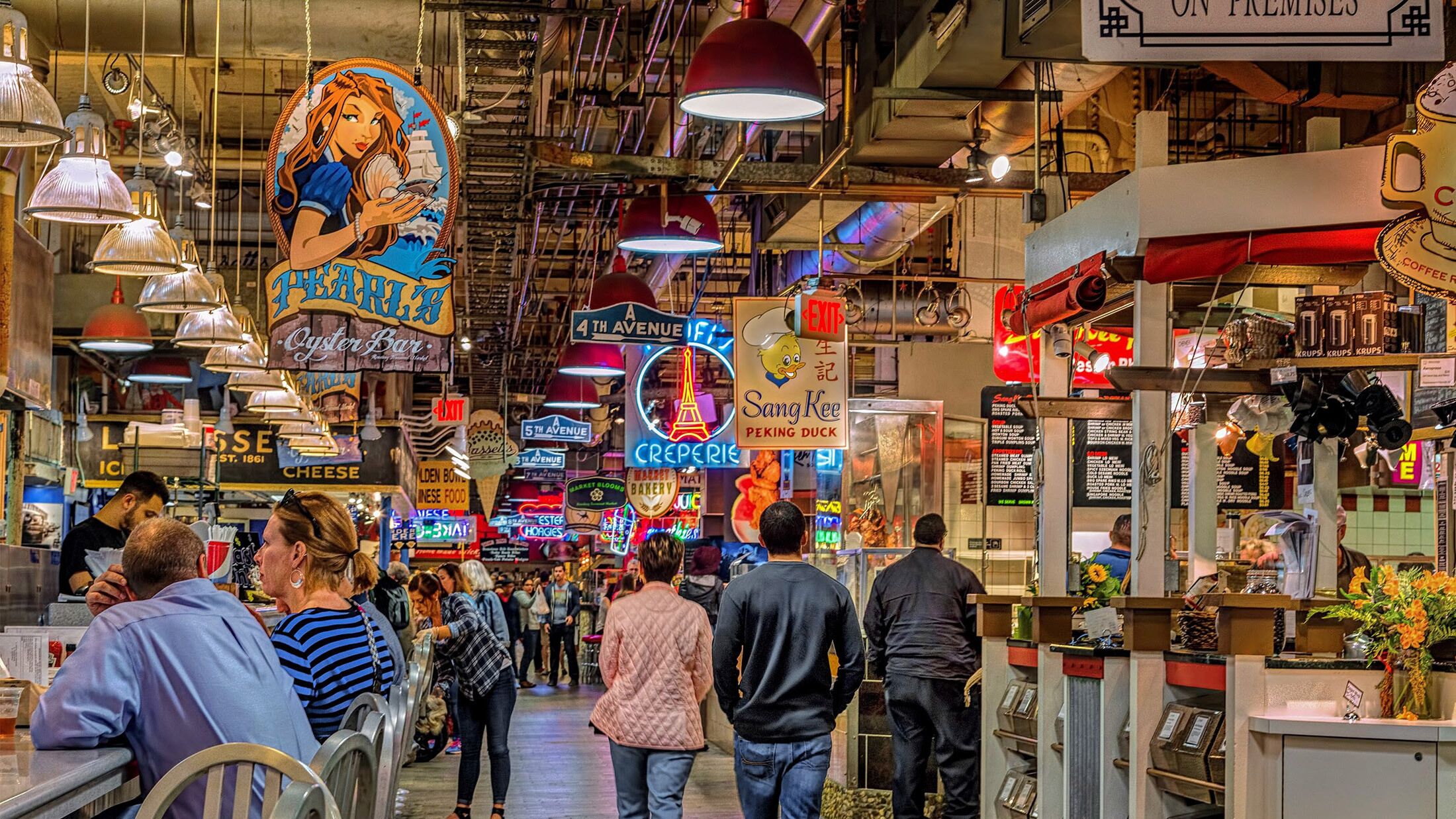 A bustling indoor market with various food stalls and shops, including a visible oyster bar and a creperie.