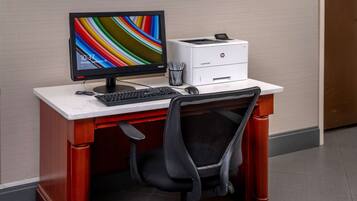 A wooden desk with a computer monitor, keyboard, and HP printer.