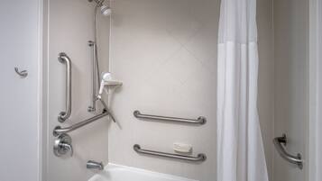 Un baño con bañera, barras de apoyo, ducha y cortina blanca.