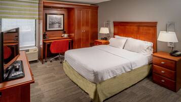 A hotel room with a bed, desk, chair, and a television.