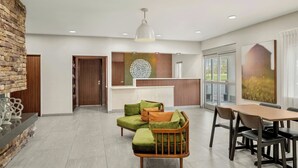 A modern living room with a sectional sofa, a wooden coffee table, and a dining area with a wooden table and chairs. - Fairfield by Marriott Mt Pleasant (Mount Pleasant)