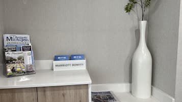 A hotel reception desk with a stack of brochures, a white vase with a plant, and a sign that reads "MARRIOTT BONVOY".
