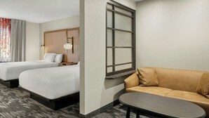 A hotel room with two beds, a sofa, a small table, and a window with blinds. - Fairfield by Marriott Mt Pleasant (Mount Pleasant)