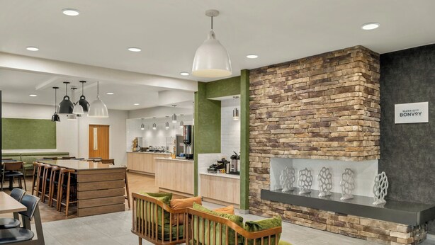 A modern hotel lobby with a stone accent wall, a reception desk, and a seating area with green upholstered chairs. - Fairfield by Marriott Mt Pleasant (Mount Pleasant)