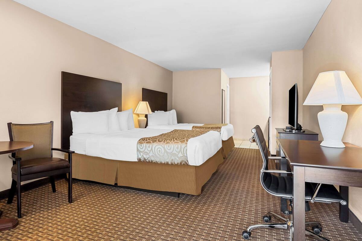 Une chambre d’hôtel avec un grand lit, un bureau, une chaise et un téléviseur.