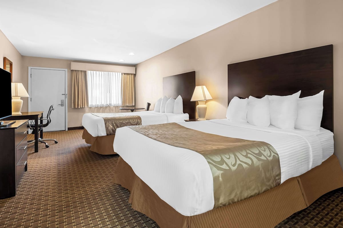 Une chambre d’hôtel avec deux lits, un bureau et une chaise.