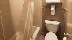A bathroom with a shower, toilet, and towel rack. - Colonial Inn Monahans (Monahans)